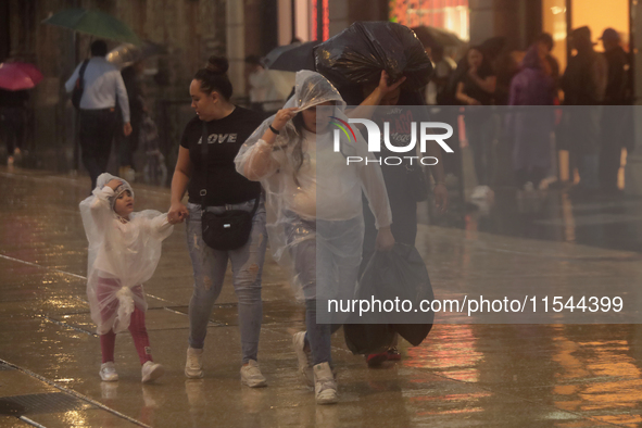 Passersby walk in the rain on Madero Avenue in Mexico City, Mexico, on September 3, 2024, on the eve of Mexican Independence Day on Septembe...