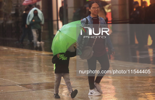 Passersby walk in the rain on Madero Avenue in Mexico City, Mexico, on September 3, 2024, on the eve of Mexican Independence Day on Septembe...