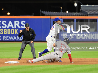 New York Mets shortstop Francisco Lindor #12 leaps over Boston Red Sox Rafael Devers #11 for the double play during the baseball game agains...