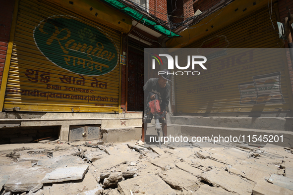 A construction worker drills around the walkways in Kathmandu, Nepal, on August 4, 2024. 