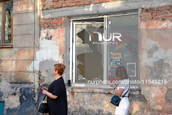 Two women walk past a window broken by the shock wave from the Russian missile attack in the Zaliznychnyi district of Lviv, Ukraine, on Sept...