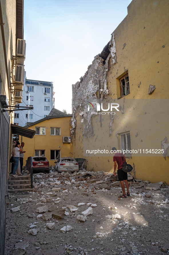 People stand outside a residential building damaged by the Russian missile attack in the Zaliznychnyi district in Lviv, Ukraine, on Septembe...