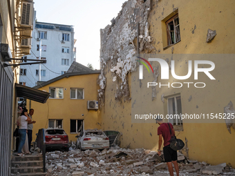 People stand outside a residential building damaged by the Russian missile attack in the Zaliznychnyi district in Lviv, Ukraine, on Septembe...