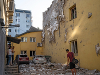 People stand outside a residential building damaged by the Russian missile attack in the Zaliznychnyi district in Lviv, Ukraine, on Septembe...