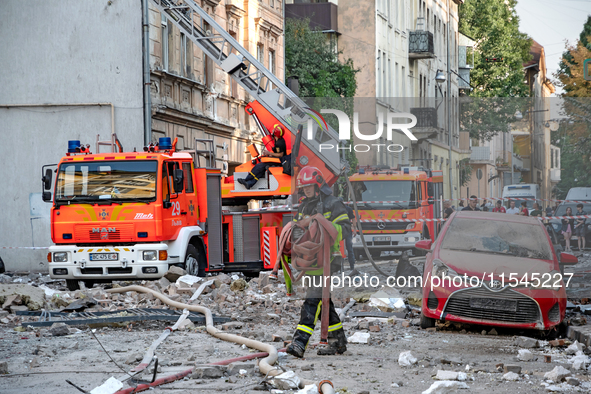 A firefighter carries a hose during a response effort to the Russian missile attack in the Zaliznychnyi district of Lviv, Ukraine, on Septem...