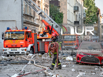 A firefighter carries a hose during a response effort to the Russian missile attack in the Zaliznychnyi district of Lviv, Ukraine, on Septem...