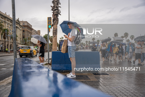 Tourists and locals walk through the city on a rainy September morning in Barcelona, Spain, on September 4, 2024. These first two weeks of S...