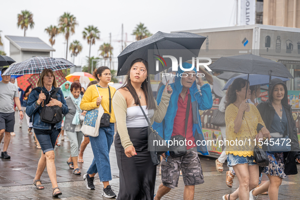 Tourists and locals walk through the city on a rainy September morning in Barcelona, Spain, on September 4, 2024. These first two weeks of S...