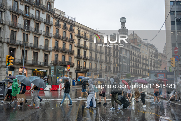 Tourists and locals walk through the city on a rainy September morning in Barcelona, Spain, on September 4, 2024. These first two weeks of S...