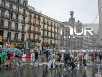 Tourists and locals walk through the city on a rainy September morning in Barcelona, Spain, on September 4, 2024. These first two weeks of S...