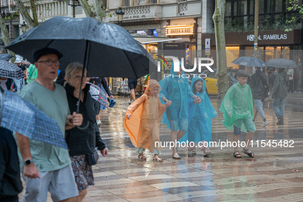 Tourists and locals walk through the city on a rainy September morning in Barcelona, Spain, on September 4, 2024. These first two weeks of S...