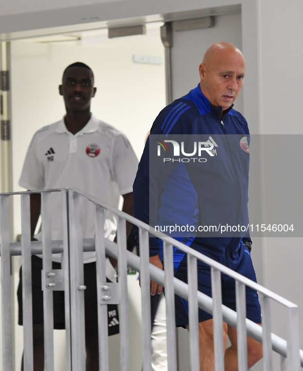 Qatar national team head coach Marquez Lopez (R) and player Moez Al Ali (L) arrive for the press conference at Ahmad Bin Ali Stadium in Al R...