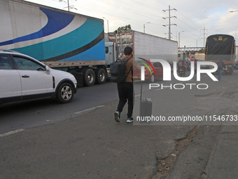 A person walks with a suitcase as truckers block the north of the city in Bogota, Colombia, on September 4, 2024. Truckers mainly protest ag...