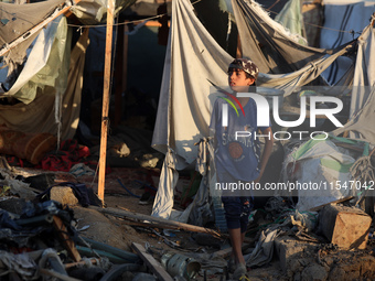 A Palestinian boy inspects the site of an Israeli strike on tents for displaced people inside Al-Aqsa Martyrs Hospital amid the Israel-Hamas...