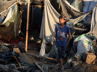 A Palestinian boy inspects the site of an Israeli strike on tents for displaced people inside Al-Aqsa Martyrs Hospital amid the Israel-Hamas...