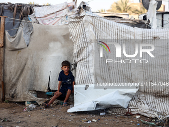 A Palestinian boy inspects the site of an Israeli strike on tents for displaced people inside Al-Aqsa Martyrs Hospital amid the Israel-Hamas...