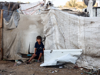 A Palestinian boy inspects the site of an Israeli strike on tents for displaced people inside Al-Aqsa Martyrs Hospital amid the Israel-Hamas...