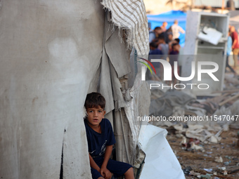 A Palestinian boy inspects the site of an Israeli strike on tents for displaced people inside Al-Aqsa Martyrs Hospital amid the Israel-Hamas...