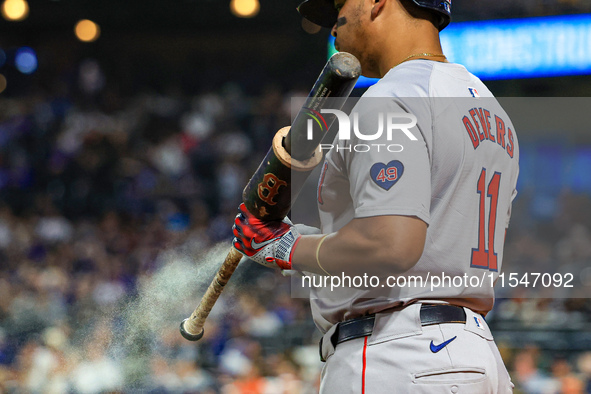 Rafael Devers #11 of the Boston Red Sox sprays his bat with a sticky substance while on deck during the eighth inning of the baseball game a...