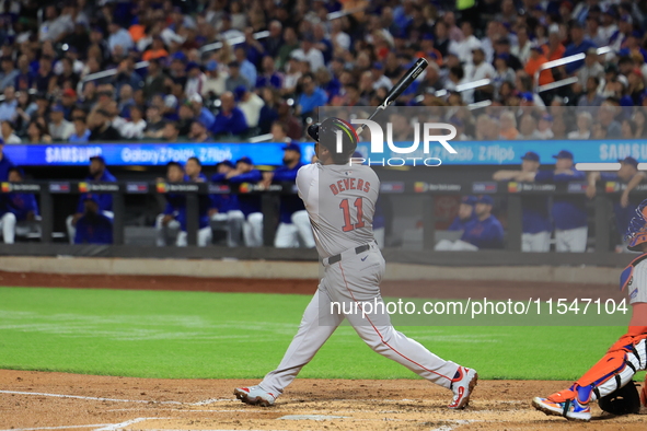 Rafael Devers #11 of the Boston Red Sox hits a sacrifice fly during the third inning of the baseball game against the New York Mets at Citi...