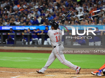 Rafael Devers #11 of the Boston Red Sox hits a sacrifice fly during the third inning of the baseball game against the New York Mets at Citi...