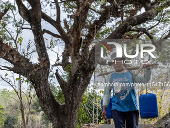 A villager carries water containers after collecting water for their livestock and plantation during the drought season in Tepus Village, Gu...