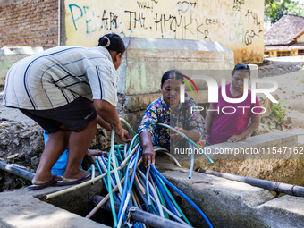 Residents fetch water from the only source by sucking it up and flowing it through a hose to their house during the drought season in Selopa...