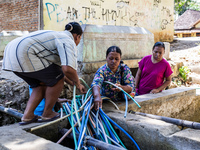 Residents fetch water from the only source by sucking it up and flowing it through a hose to their house during the drought season in Selopa...