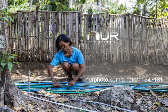 A woman connects a water hose to the only water source to her house during drought season in Selopamioro Village, Bantul Regency, Yogyakarta...