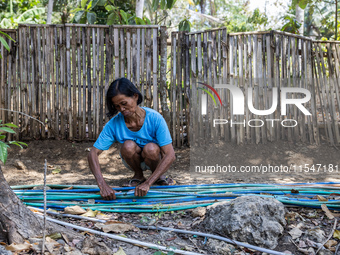 A woman connects a water hose to the only water source to her house during drought season in Selopamioro Village, Bantul Regency, Yogyakarta...