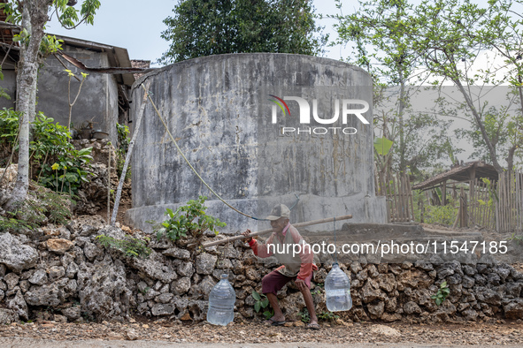 A villager carries water containers after collecting water for needs at his house during the drought season in Tepus Village, Gunung Kidul R...