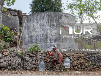 A villager carries water containers after collecting water for needs at his house during the drought season in Tepus Village, Gunung Kidul R...