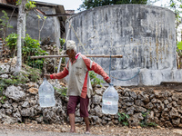 A villager carries water containers after collecting water for needs at his house during the drought season in Tepus Village, Gunung Kidul R...