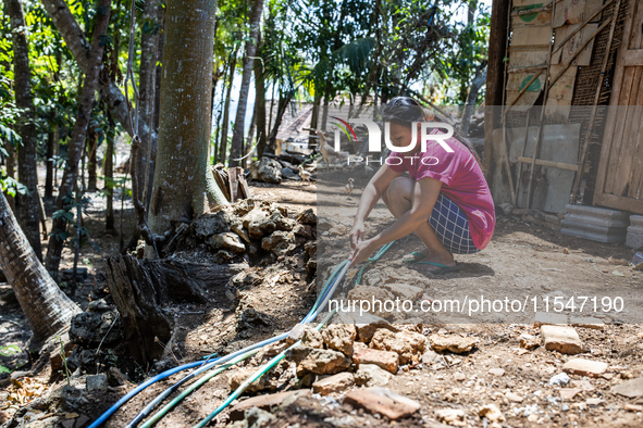 A woman connects a water hose to the only water source to her house during drought season in Selopamioro Village, Bantul Regency, Yogyakarta...