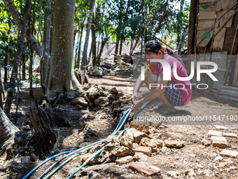 A woman connects a water hose to the only water source to her house during drought season in Selopamioro Village, Bantul Regency, Yogyakarta...