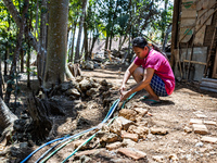 A woman connects a water hose to the only water source to her house during drought season in Selopamioro Village, Bantul Regency, Yogyakarta...