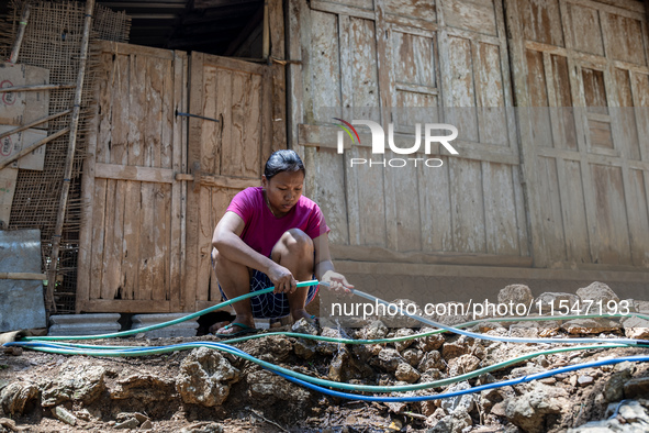 A woman connects a water hose to the only water source to her house during drought season in Selopamioro Village, Bantul Regency, Yogyakarta...