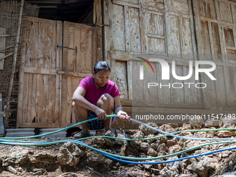 A woman connects a water hose to the only water source to her house during drought season in Selopamioro Village, Bantul Regency, Yogyakarta...