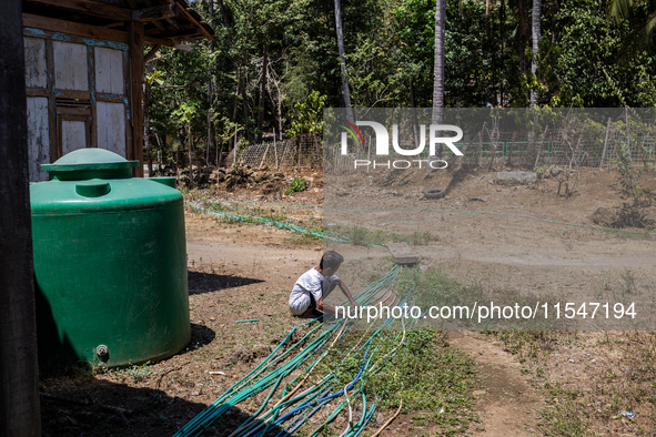 A man connects a water hose to the only water source to his house during drought season in Selopamioro Village, Bantul Regency, Yogyakarta P...