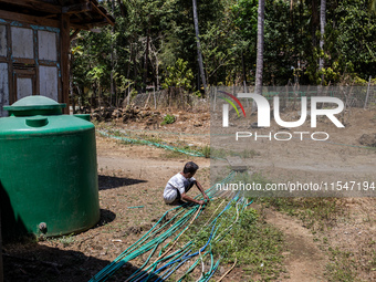 A man connects a water hose to the only water source to his house during drought season in Selopamioro Village, Bantul Regency, Yogyakarta P...