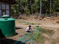 A man connects a water hose to the only water source to his house during drought season in Selopamioro Village, Bantul Regency, Yogyakarta P...