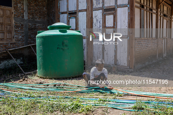 A man connects a water hose to the only water source to his house during drought season in Selopamioro Village, Bantul Regency, Yogyakarta P...