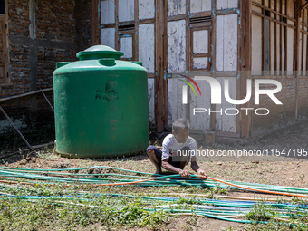 A man connects a water hose to the only water source to his house during drought season in Selopamioro Village, Bantul Regency, Yogyakarta P...