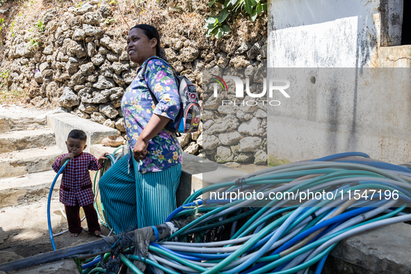 A woman connects a water hose to the only water source to her house during drought season in Selopamioro Village, Bantul Regency, Yogyakarta...