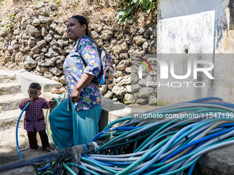 A woman connects a water hose to the only water source to her house during drought season in Selopamioro Village, Bantul Regency, Yogyakarta...