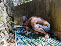 A man takes water from the only source of water by sucking it up and flowing it through a hose to his house during drought season in Selopam...