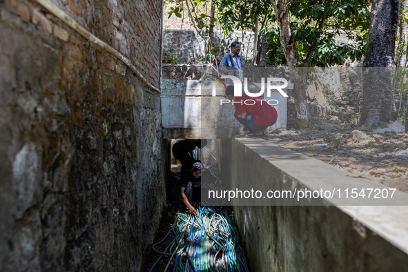 Residents fetch water from the only source by sucking it up and flowing it through a hose to their house during the drought season in Selopa...