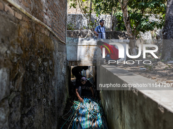 Residents fetch water from the only source by sucking it up and flowing it through a hose to their house during the drought season in Selopa...