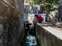 Residents fetch water from the only source by sucking it up and flowing it through a hose to their house during the drought season in Selopa...