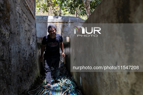 A man walks with a water hose as he directs it to his house during drought season in Selopamioro Village, Bantul Regency, Yogyakarta Provinc...